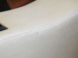 a close up of a white chair with a black button on it
