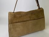 the small tan purse is sitting on a white surface