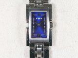 une montre en argent au cadran bleu posée sur une serviette blanche