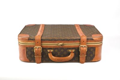 une valise marron et beige posée sur une surface blanche