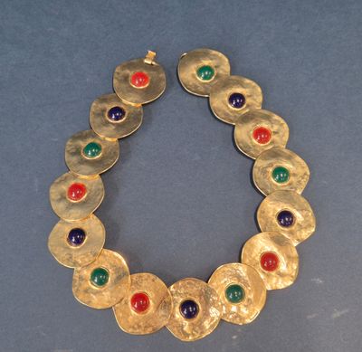 a close up of a gold bracelet with multi colored stones