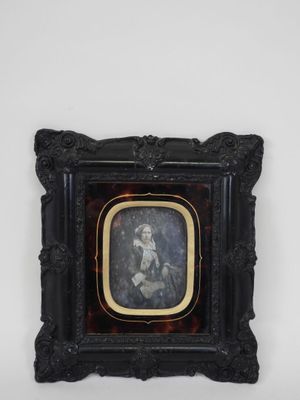 an old picture of a woman holding a baby in a black frame