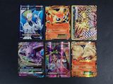 six cartes Pokémon différentes posées sur une table noire