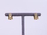 a close up of a pair of gold earrings on a stand