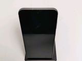 a black cell phone on a stand on a white surface