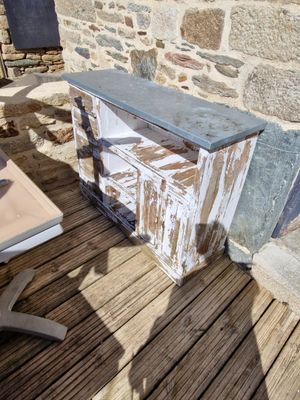une table en bois posée sur une terrasse en bois, avec un mur en pierre en arrière-plan