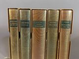 five books are lined up in a row on a gray surface