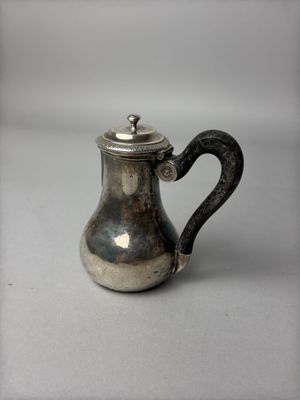 une cafetière en argent avec une anse, posée sur une table