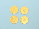 four pieces of gold coins sitting on top of a blue surface