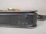 a black purse that has a gold ring on it