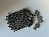 sac à main en cotte de mailles argentée, avec une chaîne et un pompon, sur un fond blanc