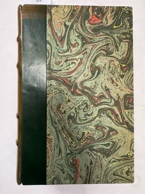 un vieux livre posé sur une table blanche à côté d'un livre noir