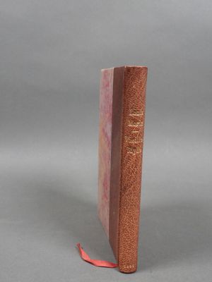 un livre marron sur lequel est posé un ruban rouge