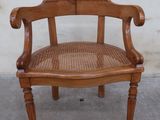 une chaise en bois avec une assise tressée, posée sur un sol en béton