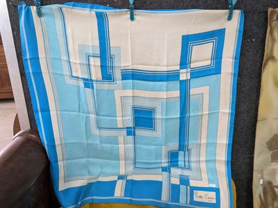 une écharpe bleue et blanche accrochée au mur à côté d'une chaise marron