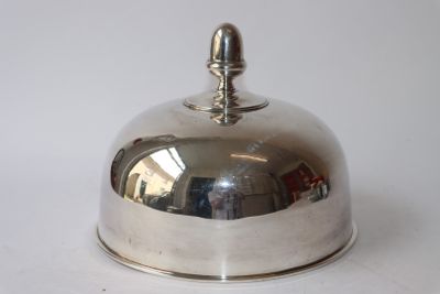 une assiette en argent ornée d'une clochette, posée sur un fond blanc