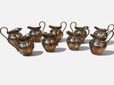 four small metal vases with handles and handles on a white surface