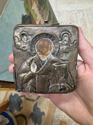 someone is holding a small metal box with a picture of jesus on it