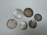 six types différents de pièces d'argent sur une surface blanche