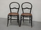 deux chaises noires à assise en osier dans une pièce blanche