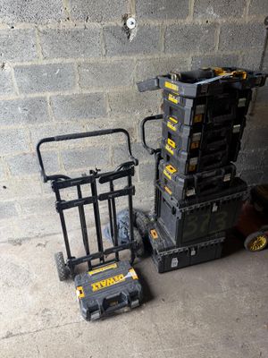 une pile de cartons et un diable près d'un mur de briques