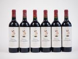 six bottles of red wine are lined up on a white surface