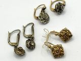 trois paires de boucles d'oreilles et une paire de boucles d'oreilles posées sur une surface blanche