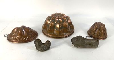 quatre types différents de moules à gâteaux posés sur un plan de travail blanc