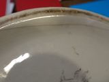 a close up of a white bowl with brown marks on it