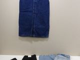 deux paires de jeans bleus et une paire de bottes noires posées sur une table blanche