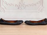 une paire de ballerines en cuir noir posées sur un parquet