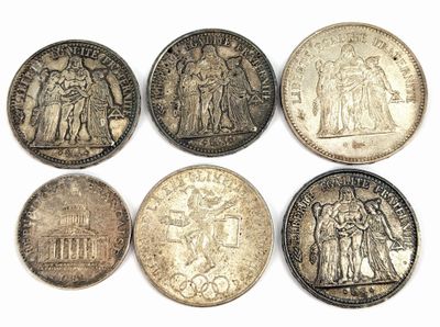 six types différents de pièces d'argent sur une surface blanche