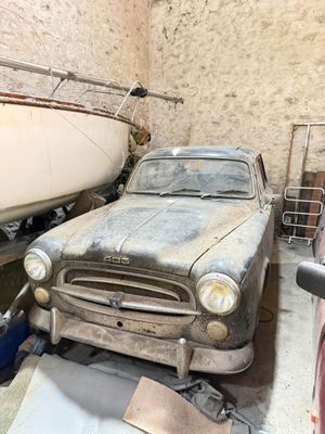 a old car parked in a garage next to a boat