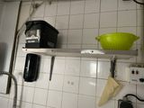 a green bowl on a white shelf in a kitchen