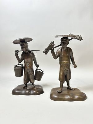 paire de figurines en bronze représentant un homme et une femme portant des seaux sur la tête