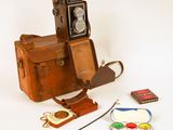 un vieil appareil photo et quelques autres objets posés sur une surface blanche