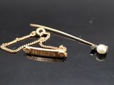 une broche en perle et en or posée sur un fond noir