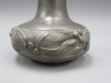 un vase en argent posé sur une table, sur fond gris