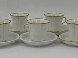 many cups and saucers sitting on a white table