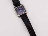 a close up of a watch on a white surface with a black strap