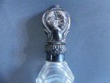 a glass bottle with a silver handle on a blue surface