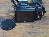a black camera sitting on a wooden table with a camera strap