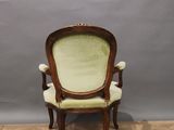 an old chair with a green upholstered seat on a wooden floor