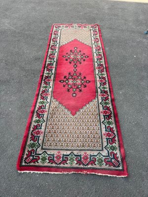 a red rug with a floral design on it on the ground