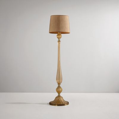 un lampadaire doré surmonté d'un abat-jour beige
