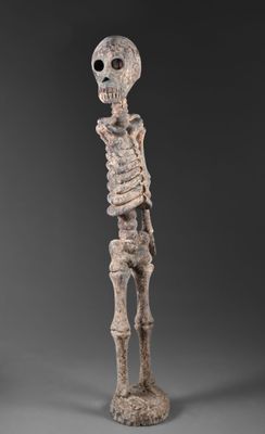 une statue représentant un squelette debout sur une surface grise