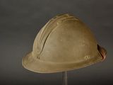 an old helmet is sitting on a stand against a gray background