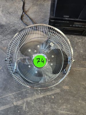 un ventilateur sur lequel est collé un autocollant vert, posé par terre