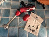 two red hand mixers on the floor next to a bag