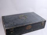 an old black suitcase sitting on top of a white surface